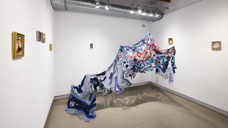 A colorful garment suspended from the ceiling with wire
