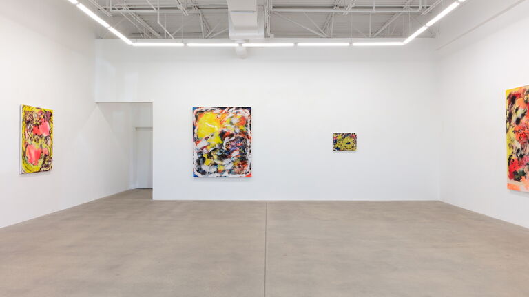 A view of a gallery with four pieces of abstract art hanging on white walls.