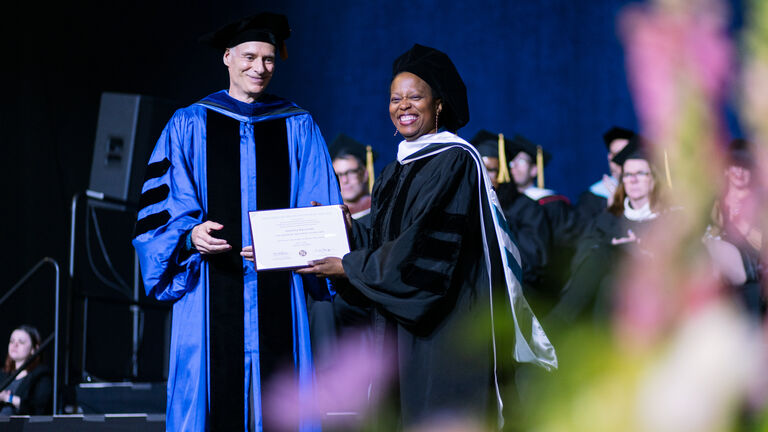 Amanda Williams, an adult Black woman, smiling while holding a degree and standing next to Martin Berger, an adult white man.