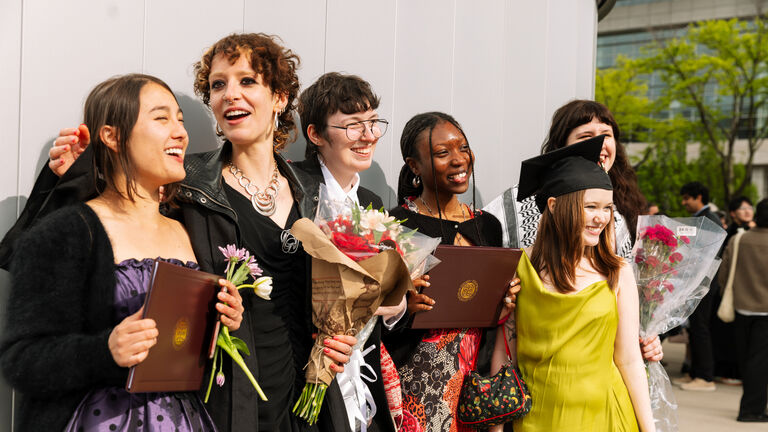 A group of six recent graduates, varying in ethnicity and gender, posing for photos while holding degrees and flowers.