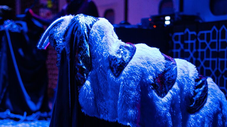 Kyle, in a slug-like creature costume, moves around under blue and purple lights.