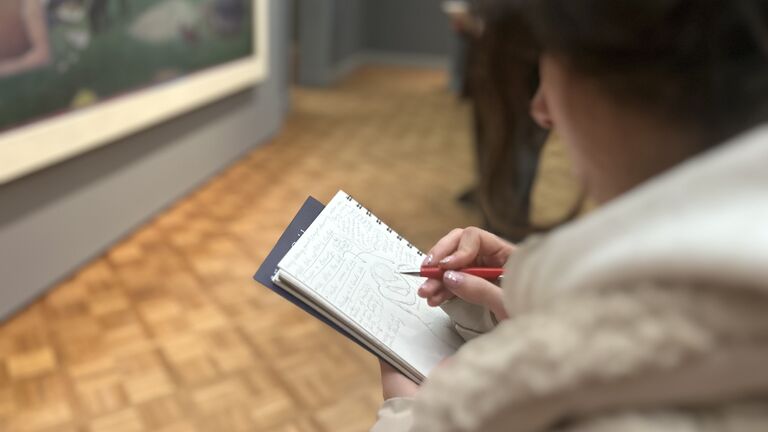 A student with a sketchpad inside a museum.