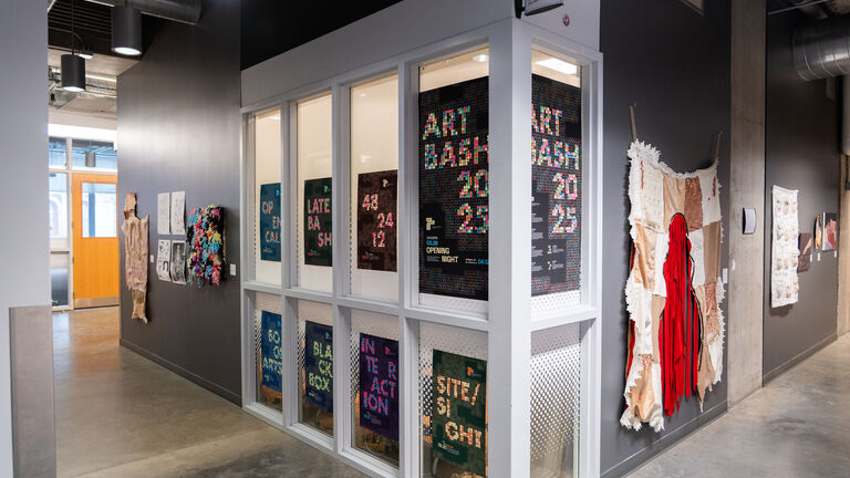 A hallway in a modern building with ARTBASH posters on the walls