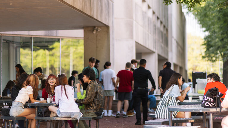 Students sit at tables outside of the 280 Building on SAIC's campus.