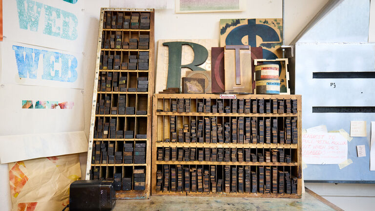 Wooden shelves full of letterpress blocks and art.