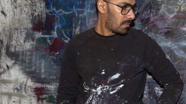 Artist Abdulrahman Hamdi stands in front of his painting