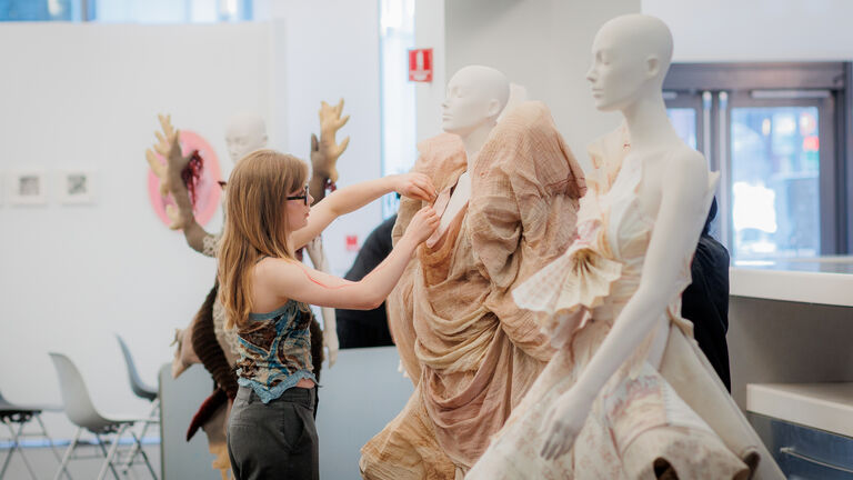 A student pins a sculptural fashion design on a mannequin