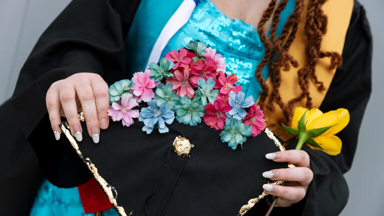 A student holds their graduation cap covered in flowers