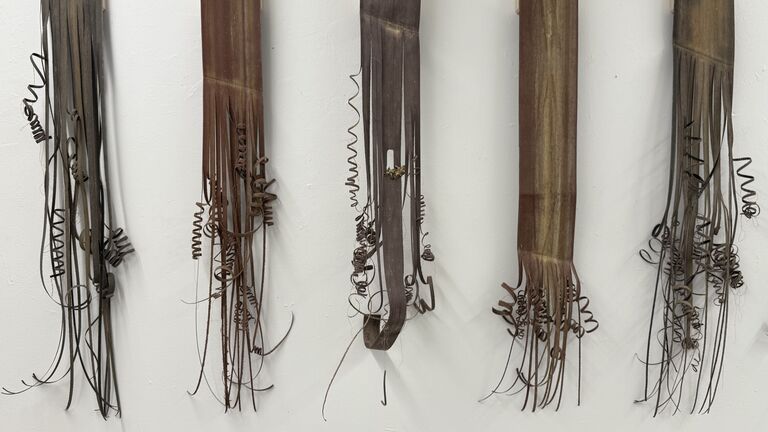 Five sculptural pieces hang on a wall