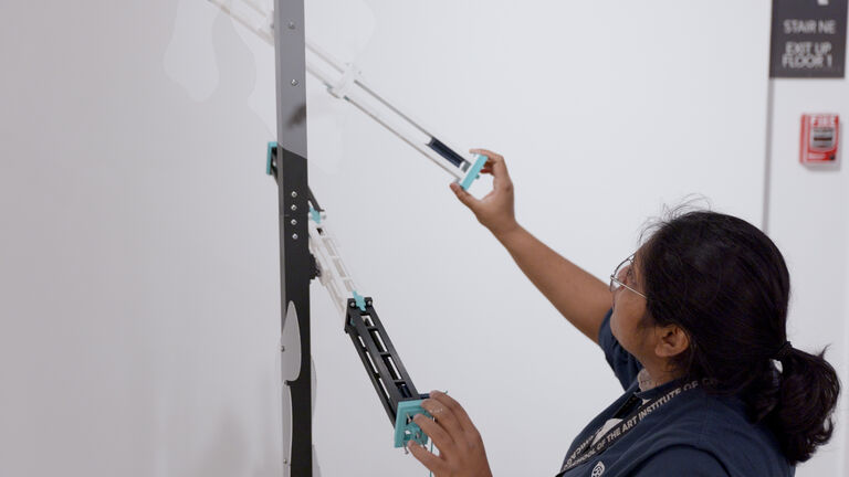 A student measures a gallery space for installation