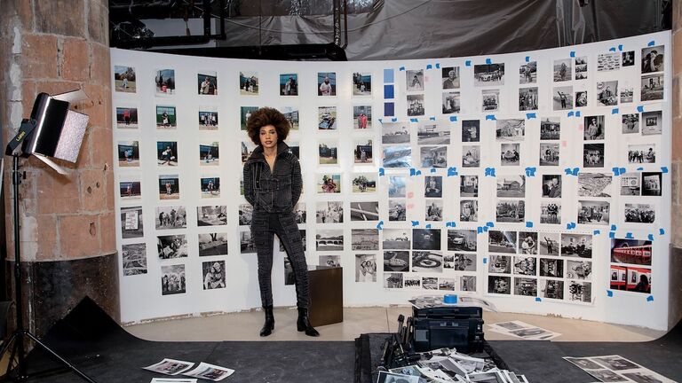 Photographer LaToya Ruby Frazier standing in front of a wall of photographs in her studio 