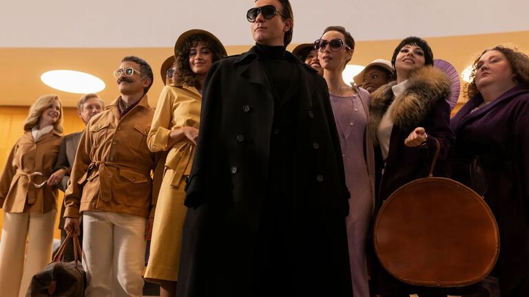 Ewan McGregor as Halston in the center, surrounded by a group of well dressed individuals.