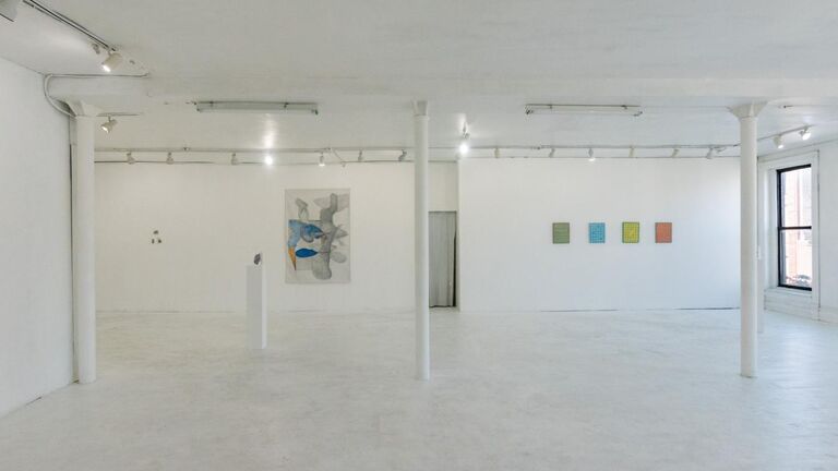 A gallery space with white walls and floors. A few pieces are hung on a wall.