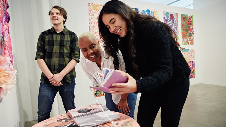 A picture of three individuals, two women and one man at an exhibit