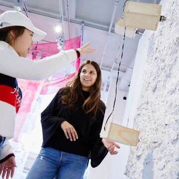 A group of students and faculty members observe a piece up in the galleries.