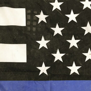 A closeup image of what appears to be a segment of a “Blue lives” flag, showing only a few stars, white stripes, and a single strip of blue below.