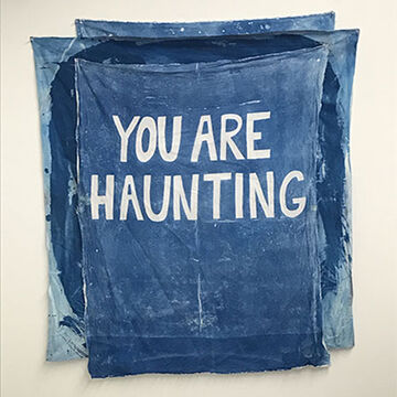 A blue piece with “You Are Haunting” written on it