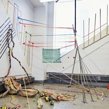 An art installation comprised of red, blue and yellow rope and black tape.