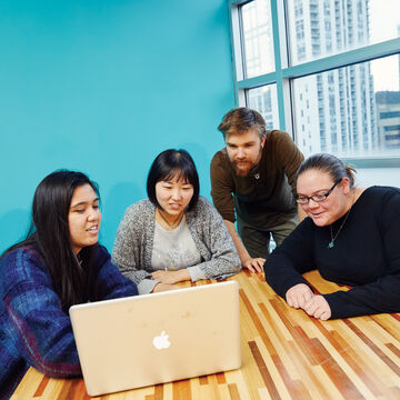 A small group of people looking at something on a computer. 