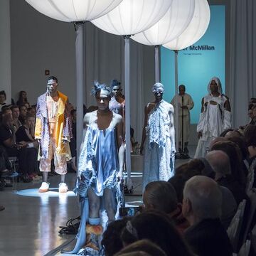 Models walking on runway with lantern lights hanging above.