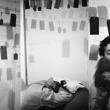 A black and white image of David Sedaris in his apartment. 