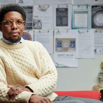 An image of J. Howard Rosier sitting at a desk in a white sweater.