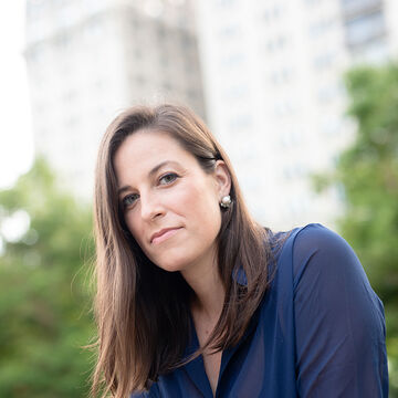 An image of Laura-Caroline de Lara sitting outside wearing a blue shirt. 