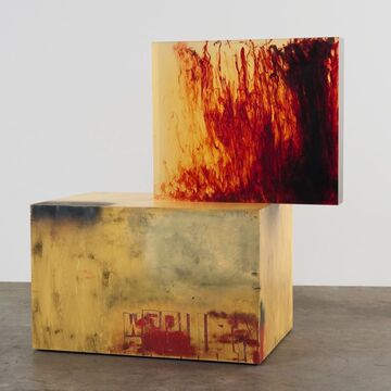 Two large red and orange boxes stacked in an open gallery. 