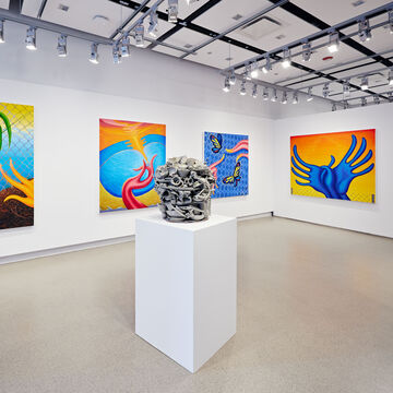 A sculpture on a pedestal in a gallery surrounded by colorful paintings