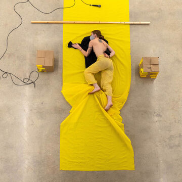 A person in yellow pants lies upon a yellow sheet