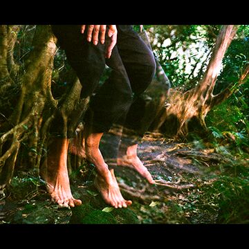 Distorted image of a person’s feet upon a mossy rock