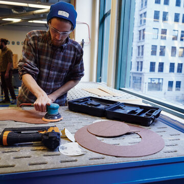 A student using a sander in the wood shop.