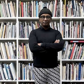 Dawit standing in front of a tall bookshelf