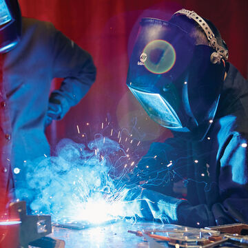 A student wearing protective gear works on a welding project