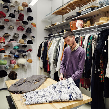 A student studies some fashion pieces at the fashion resource center