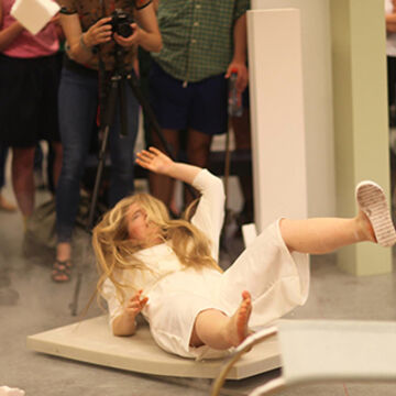 A blonde person in a white dress falling down