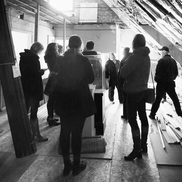 Black and white image of a group of people in an attic in the middle of renovation