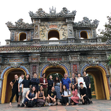 A group of students standing in front of some archways.