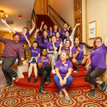 A group of SAIC students exuberantly pose at the bottom of a staircase.