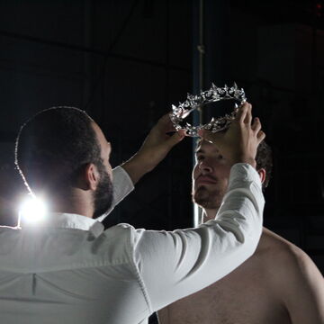One person presents another with a silver crown. 