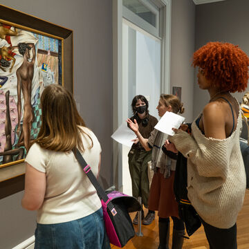 Group of students standing around and engaging with piece of art on a gallery wall.