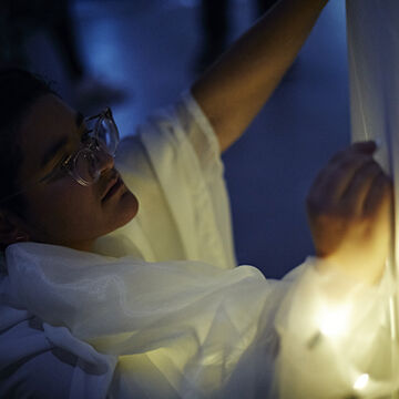 A person in glasses observes fabric