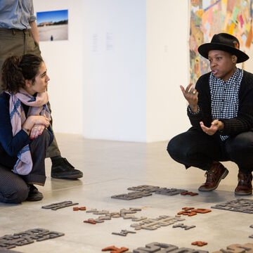 Students kneeling over an art piece they are discussing