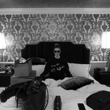 A black and white image of McKenzie Thompson sitting on a bed. 
