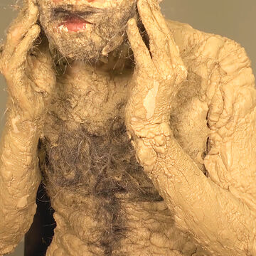 A person with clay spread over their entire body