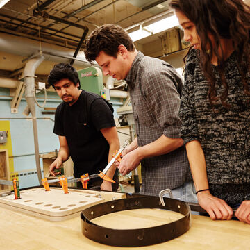 Three students working on a piece in the wood shop.