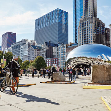 Skyscrapers in the background with the Chicago CloudGate “Bean” surrounded by people.