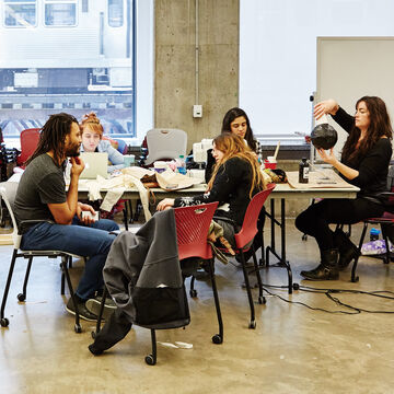 A group of students talking and working in a classroom