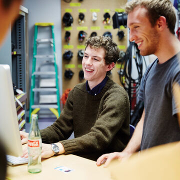 Two people working at a computer together in an equipment room. 