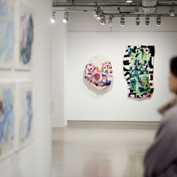 A person viewing wall art in a gallery space. 